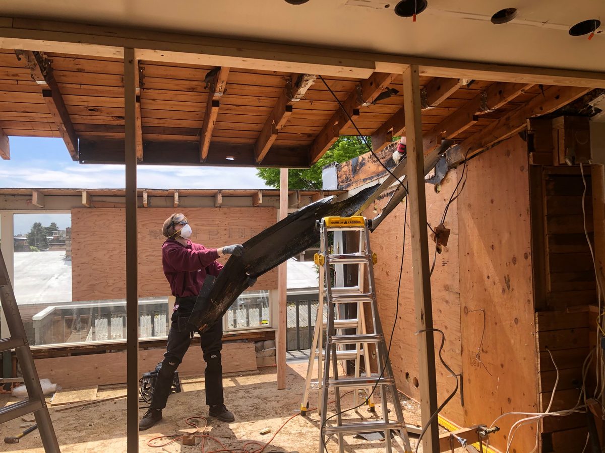 Worker manually removing a structural beam during interior demolition