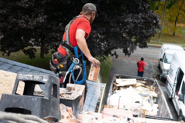 Worker manually loading demolition debris into a disposal container